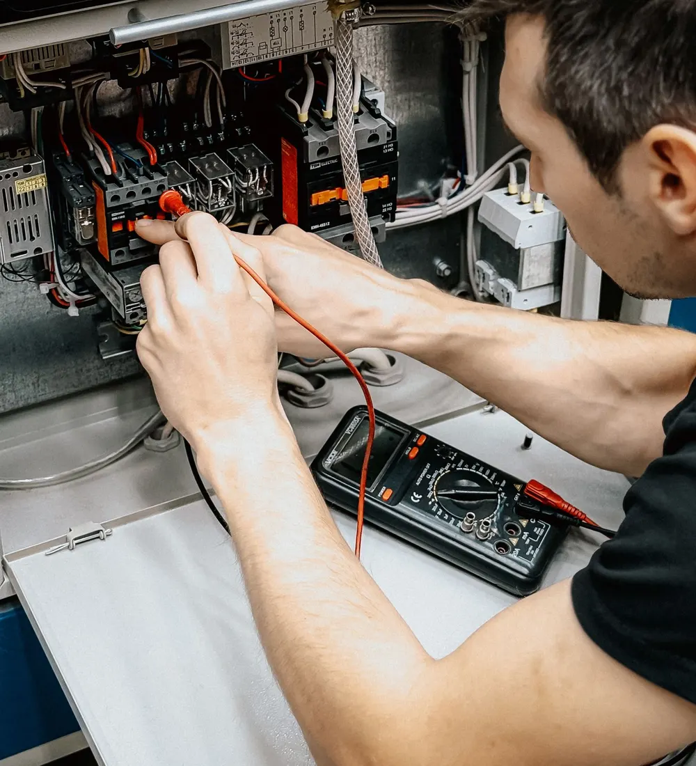 Électricien qui contrôle un tableau électrique avec un multimètre